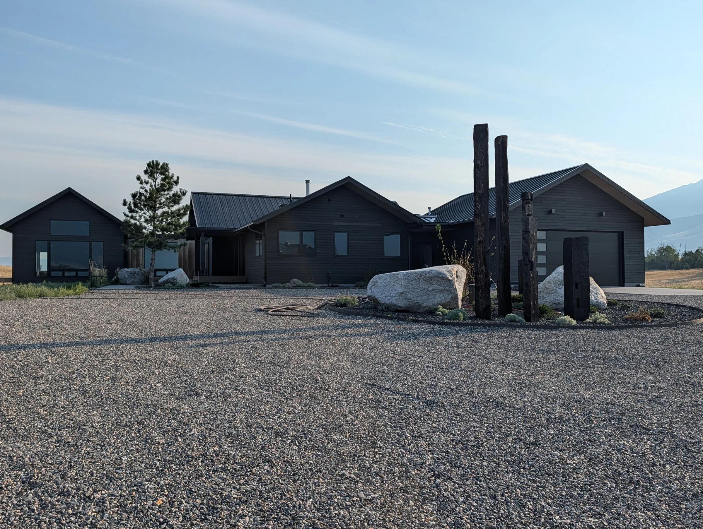 Basecamp’s charcoal-sided Parade home with gabled metal roofs, a gravel approach and mountain backdrop.