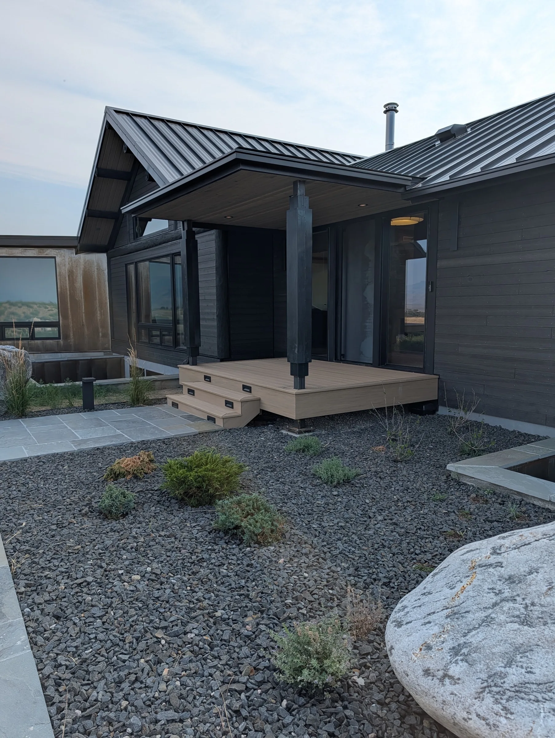 The covered entry with dark wood siding, a timber post and stone path.